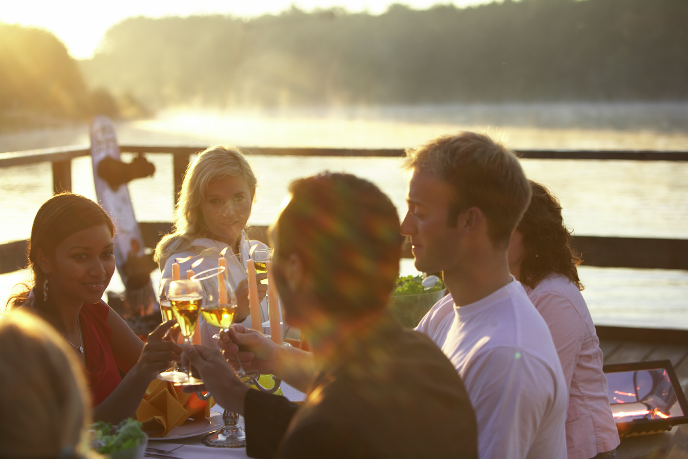 Fünf Personen an einem feierlich eingedeckten Tisch im Freien prosten sich mit gefüllten Sektgläsern zu