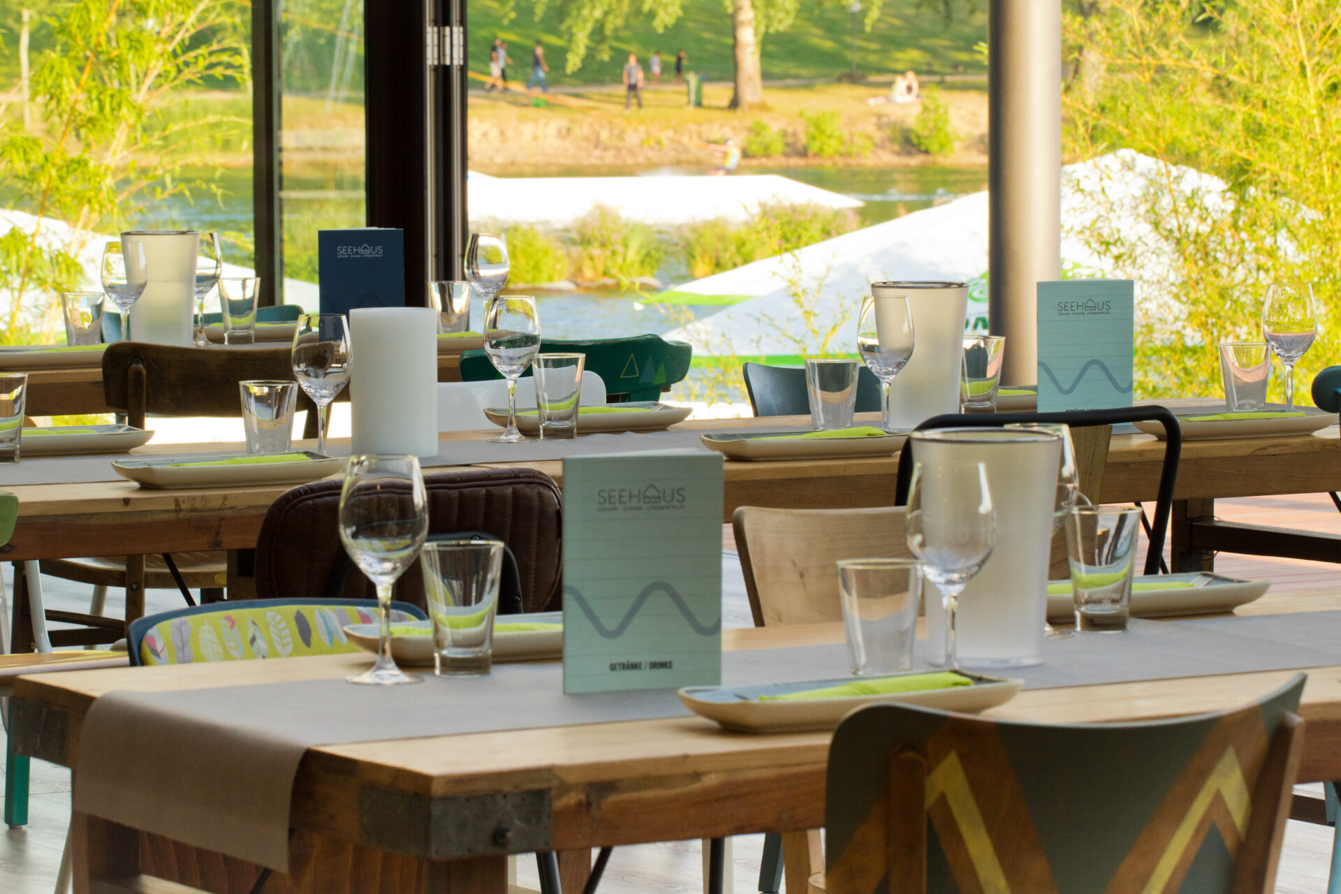 Nahaufnahme eines gedeckten Tischs im Eventraum, mit Gläsern, Tellern, Besteck und Menükarten