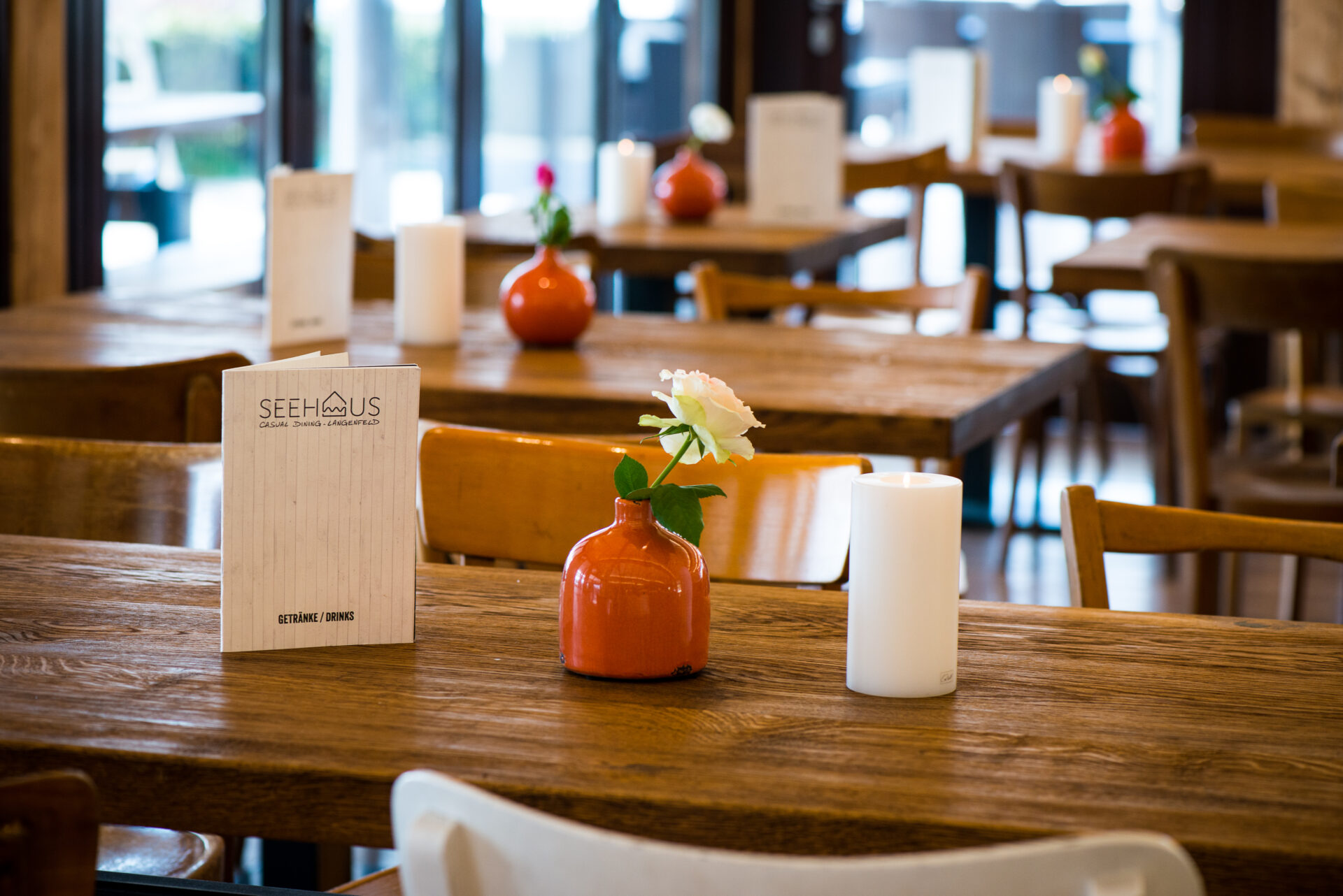 Blick in den Gastraum des Seehaus Langenfeld. Gedeckte Tische mit Blumen, Kerze und Speisekarte