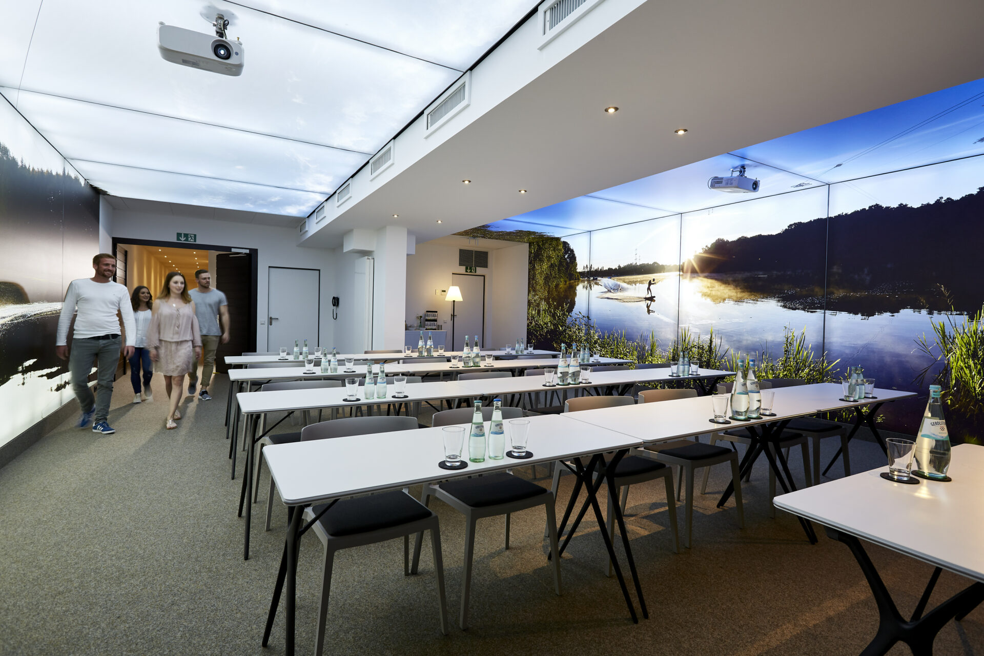 Tagungsraum mit parlamentarischer Bestuhlung inklusive Wasserflaschen auf den Tischen und dekorativen Pixlip-Wandsystemen im Hintergrund