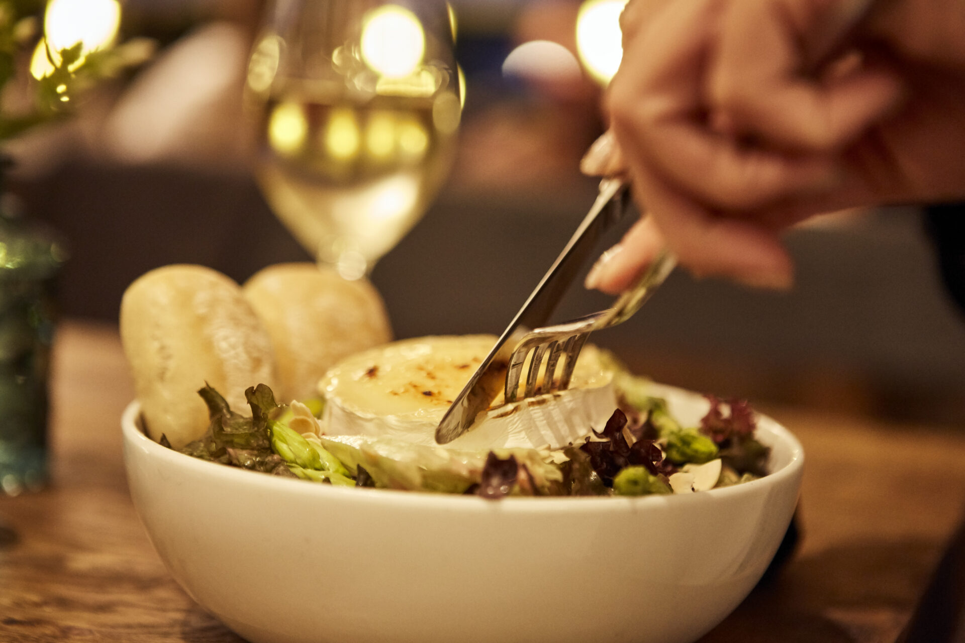 Nahaufnahme eines Ziegenkäsesalats, der gerade mit Messer und Gabel gegessen wird.