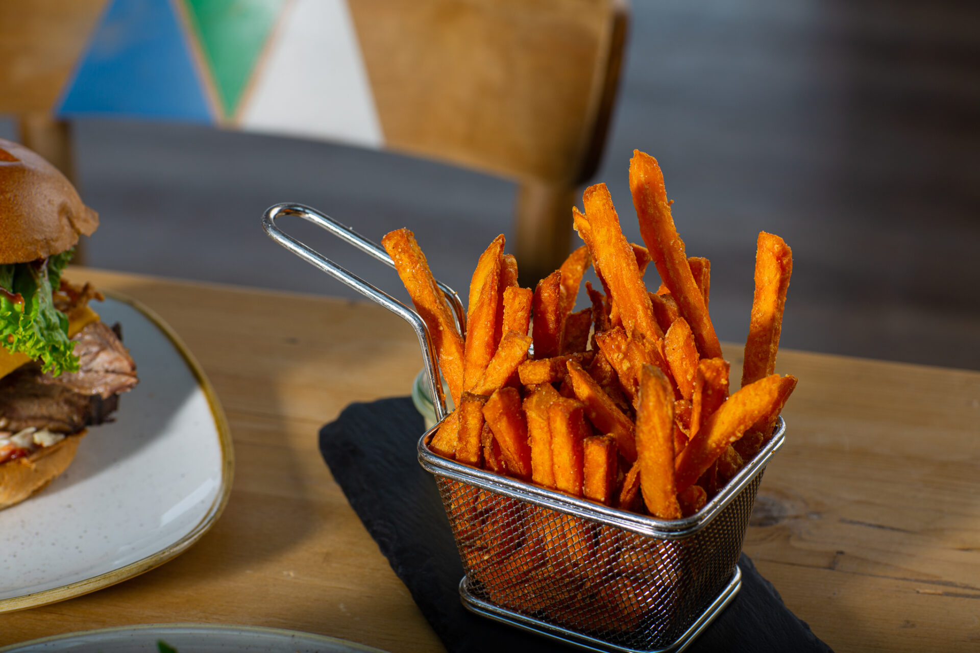 Süßkartoffelpommes angerichtet in einem kleinen Deko-Frittierkorb