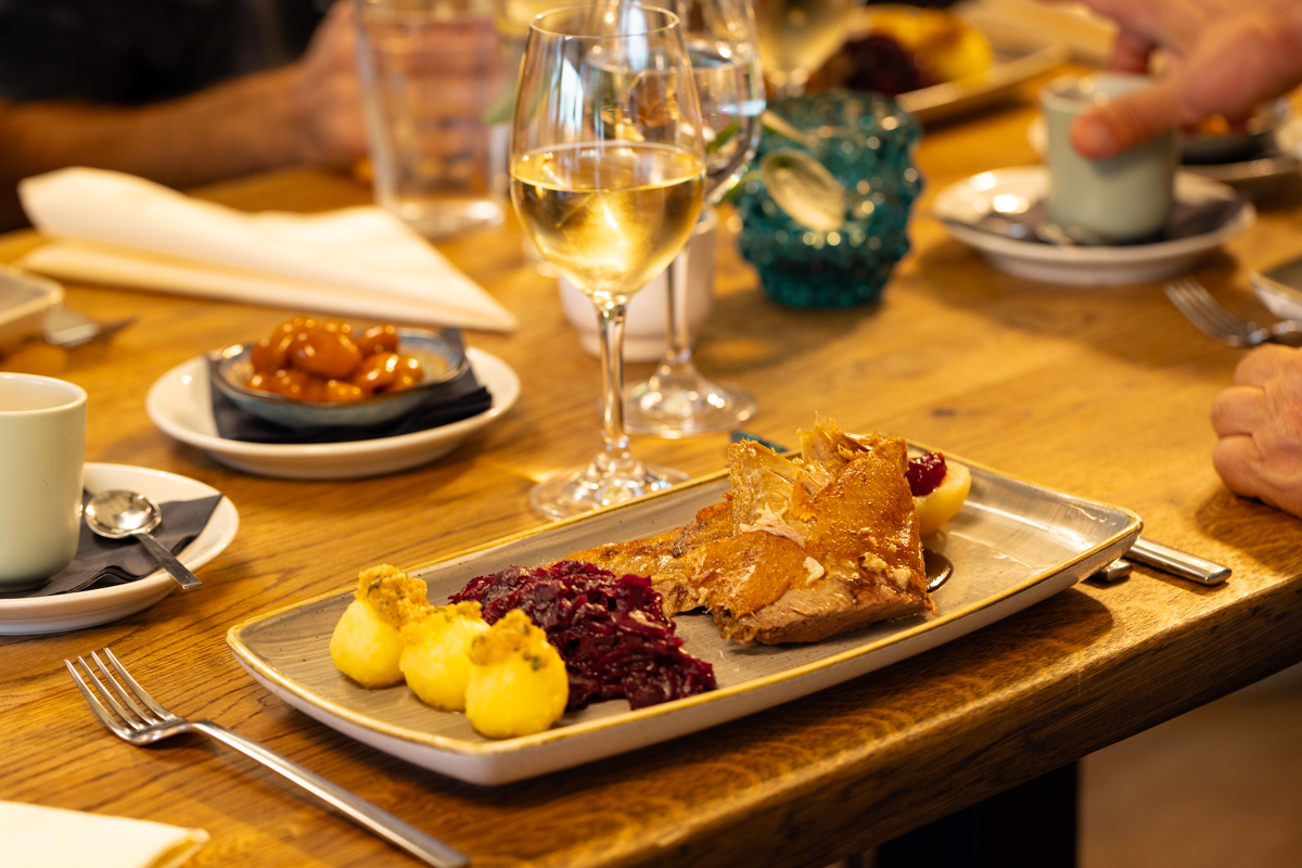 Seehaus Langenfeld Gänsekeule mit Klößen und Rotkohl auf einem Tisch mit einem Weinglas